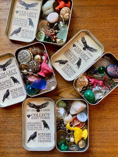 four tins filled with assorted items on top of a wooden table next to each other