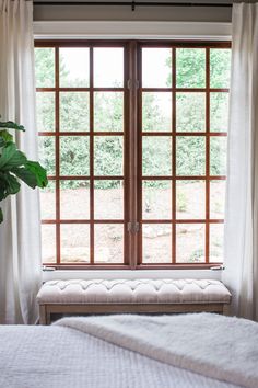 a bed sitting under a window next to a white blanket