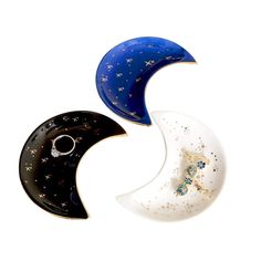 two rings are sitting on top of the moon shaped brooches, one is black and one is white