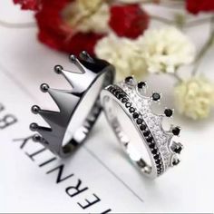 two wedding rings with black and white diamonds on them, one is wearing a crown