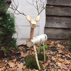 a wooden deer head sitting on top of a pile of leaves next to a tree