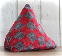 a red and grey triangle shaped pillow sitting on top of a wooden table