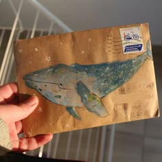 a person holding an envelope with a whale on it