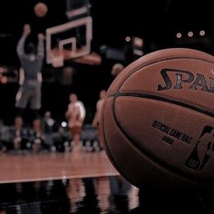 a close up of a basketball on a court with people in the background playing basketball