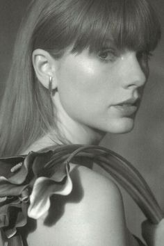 a black and white photo of a woman with long hair wearing flowered necklaces