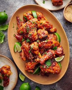 a plate full of chicken wings with limes and seasoning on the side next to it