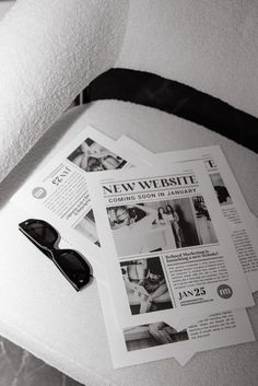 a pair of black sunglasses sitting on top of a bed next to newspapers and glasses