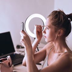 a woman is looking at herself in the mirror with her eyes closed and holding a pen