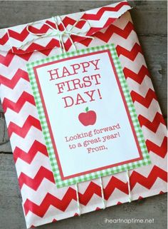 an apple next to a paper bag with the words happy first day on it