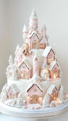 a pink and white christmas cake with lit houses on the top is decorated in snow