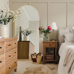 a bedroom with a bed, dresser and flowers in vases on top of it