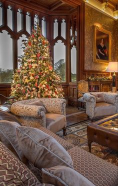 a living room with a christmas tree and couches in front of large glass windows