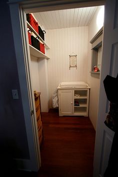 an open door leading into a small room with white walls and wood flooring in it