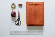 sewing supplies laid out on top of a white surface with tape, scissors and thread