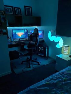 a bedroom with two computer monitors and a chair in the corner, lit up by blue lights