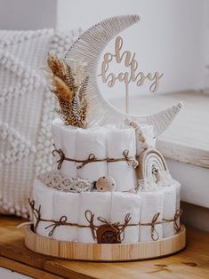 a cake made out of diapers sitting on top of a wooden tray next to a pillow