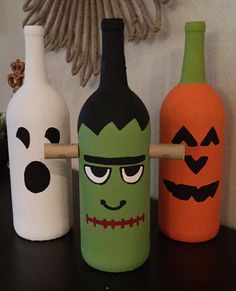 three halloween bottles with faces painted on them