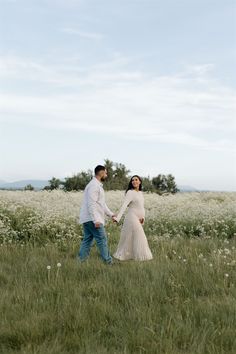 a man and woman holding hands in a field