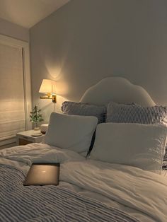 a laptop computer sitting on top of a bed in a room with white sheets and pillows