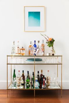 a bar cart filled with liquor bottles and glasses on top of a hard wood floor