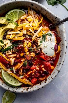 a bowl filled with chili, cheese and avocado on top of a table