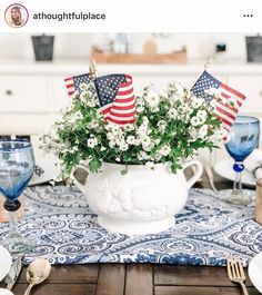 an american flag centerpiece with flowers in a white pitcher on a blue and white place mat