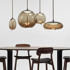 a table with four chairs and three lights hanging from it