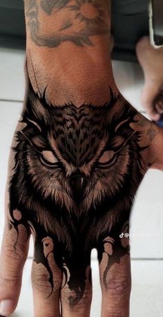 a hand with an owl tattoo on it