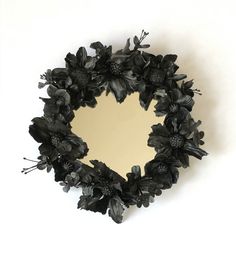 a mirror with black flowers on it and a white wall in the backround