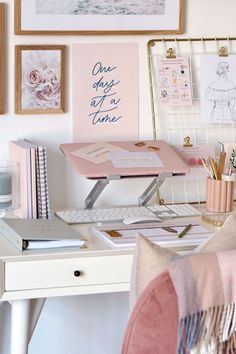 a desk with a laptop, keyboard and pictures on the wall