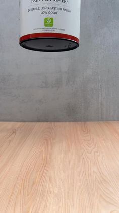 a wooden table topped with a can of paint and a light fixture hanging from the ceiling