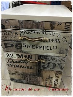 an old wooden box with some writing on it and rope attached to the top, sitting on a tile floor