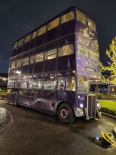 a double decker bus is parked on the side of the road in front of a tree