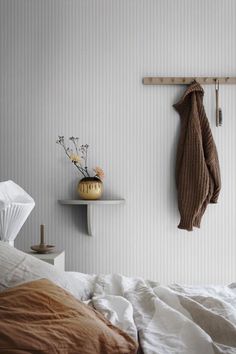 a bedroom with a coat rack on the wall and a bed in front of it