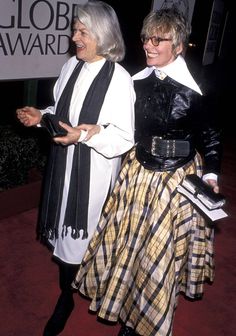 two women standing next to each other in front of a globe awards sign and smiling