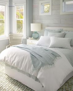 a white bed sitting in a bedroom next to two windows