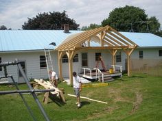 two men are working on the roof of a small white house that is being built