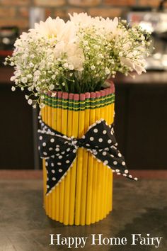 a yellow vase filled with white flowers on top of a table