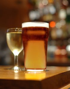 two glasses of beer sitting on top of a wooden table