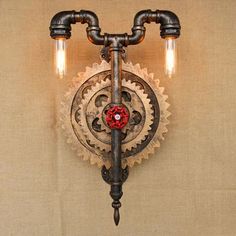 an old fashioned light fixture with two lights on it's side and gears attached to the wall