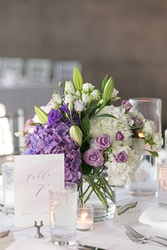 the centerpieces on this table are purple and white flowers