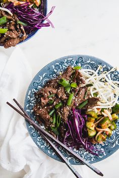 two plates filled with meat and veggies next to chopsticks