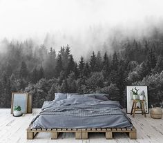 a bed sitting on top of a wooden platform in front of a forest wall mural