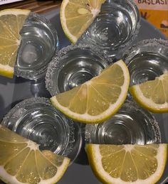 there are lemons and water in the glass cups on the tray with silver rims