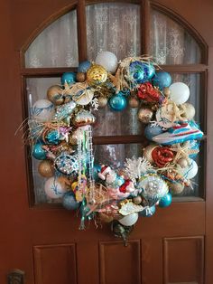 a christmas wreath on the front door of a house with ornaments hanging from it's side