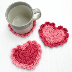 two crocheted coasters are next to a coffee cup on a white table