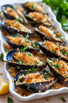 a white dish filled with cooked mussels and garnished with parsley