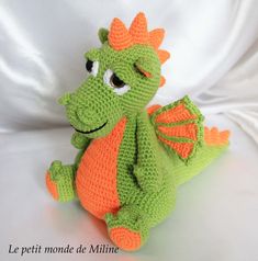 a crocheted green and orange dragon stuffed animal on a white background with the words le petit monde de miline written in french