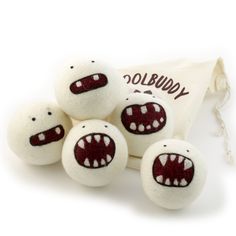 four white balls with red mouths and teeth on them are sitting next to a bag