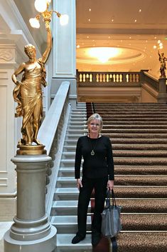 a woman standing in front of a golden statue on top of a set of stairs